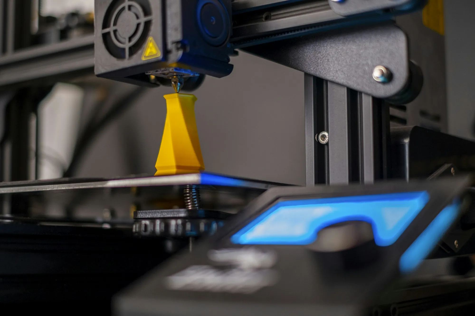 Una impresora 3D imprimiendo una pieza amarilla